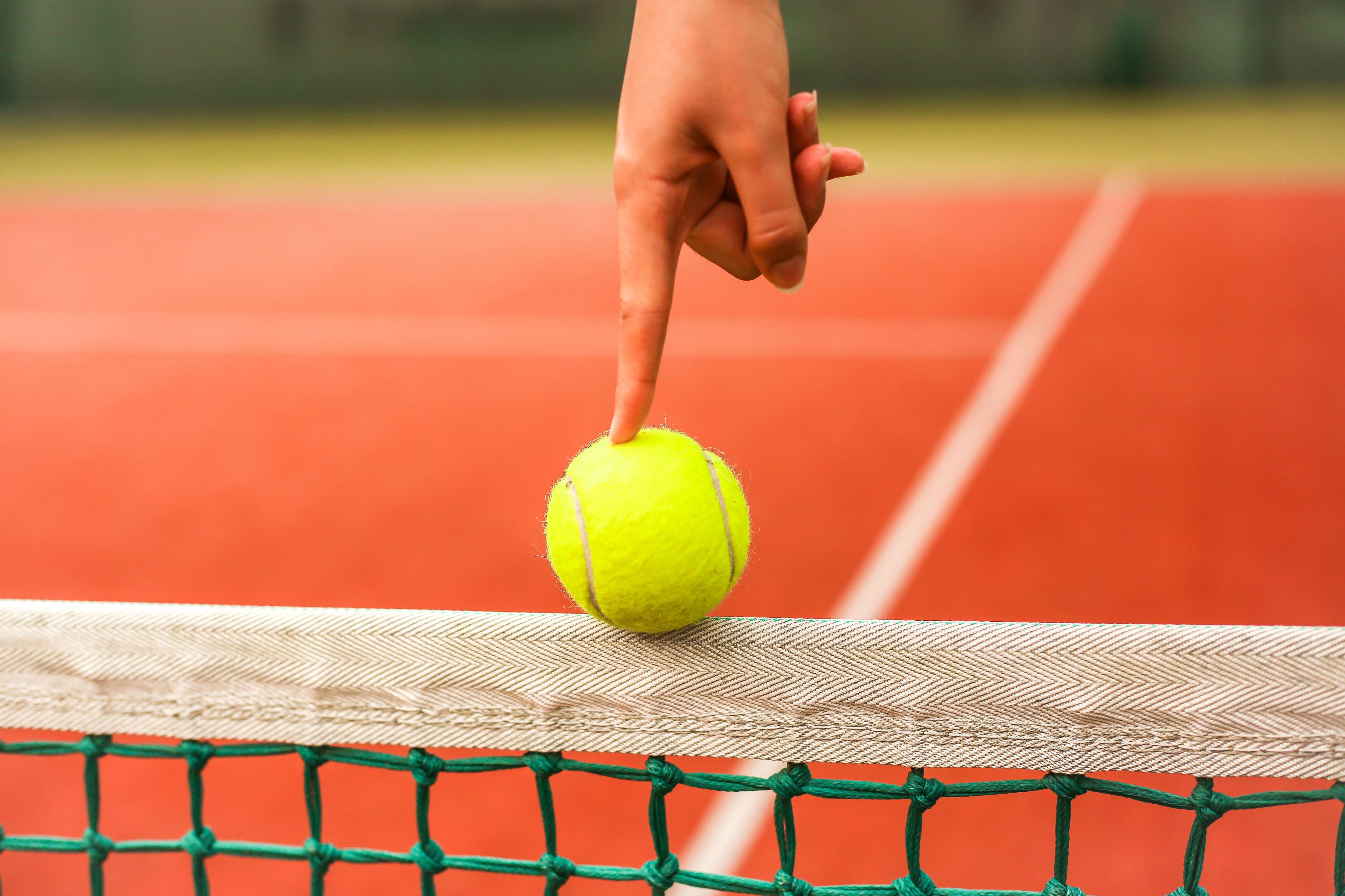 Tennisbal balancerend op een tennisnet